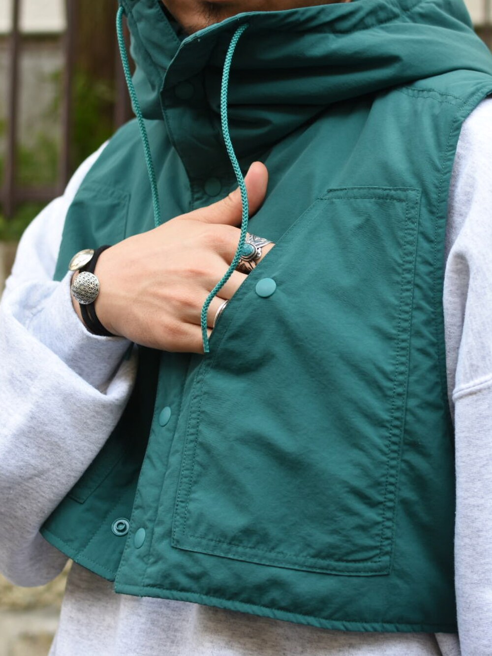 グリーン系のダウンベスト、グレー系のスウェット、ブルー系のパンツを着用したメンズの秋コーディネートの5枚目の写真