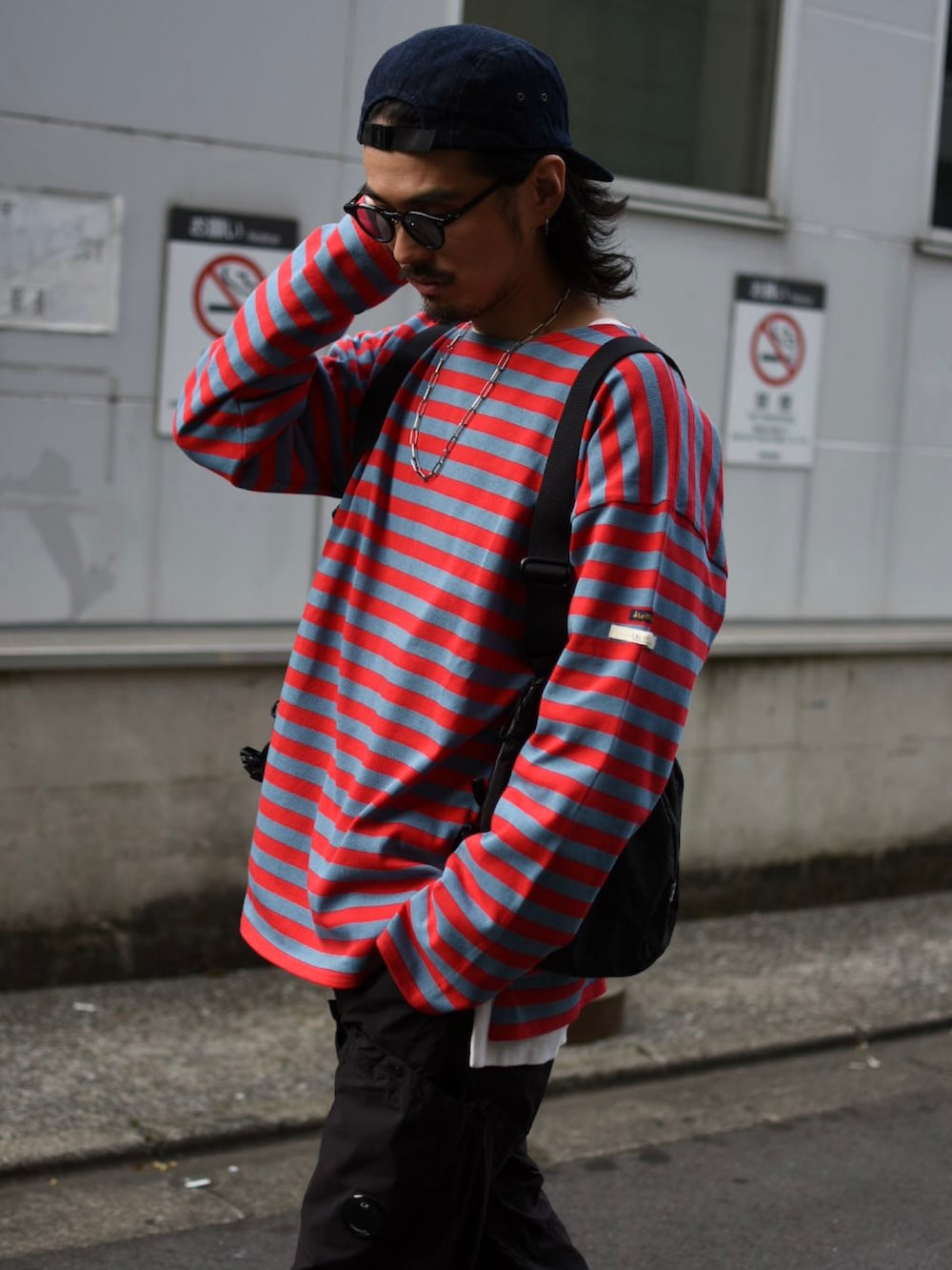 ブラック系のベスト、レッド系のTシャツ/カットソー、ブラック系のカーゴパンツを着用したメンズの春コーディネートの2枚目の写真