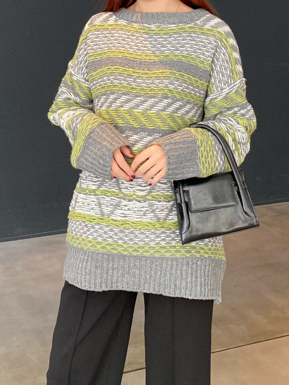 グレー系のニット/セーター、ブラック系のハンドバッグ、ブラック系のブーツを着用したレディースの冬コーディネートの2枚目の写真