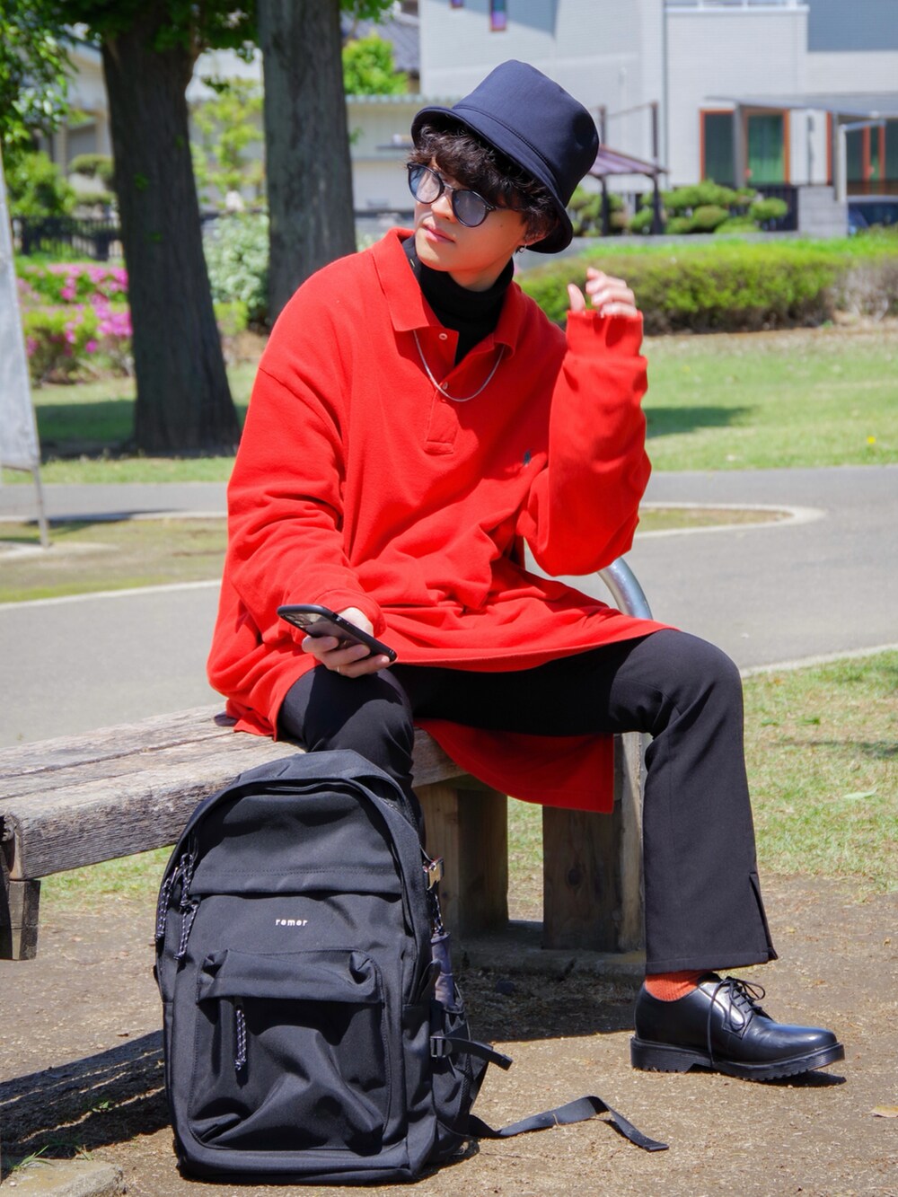 レッド系のポロシャツ、ブルー系のハットを着用したメンズの春コーディネートの2枚目の写真