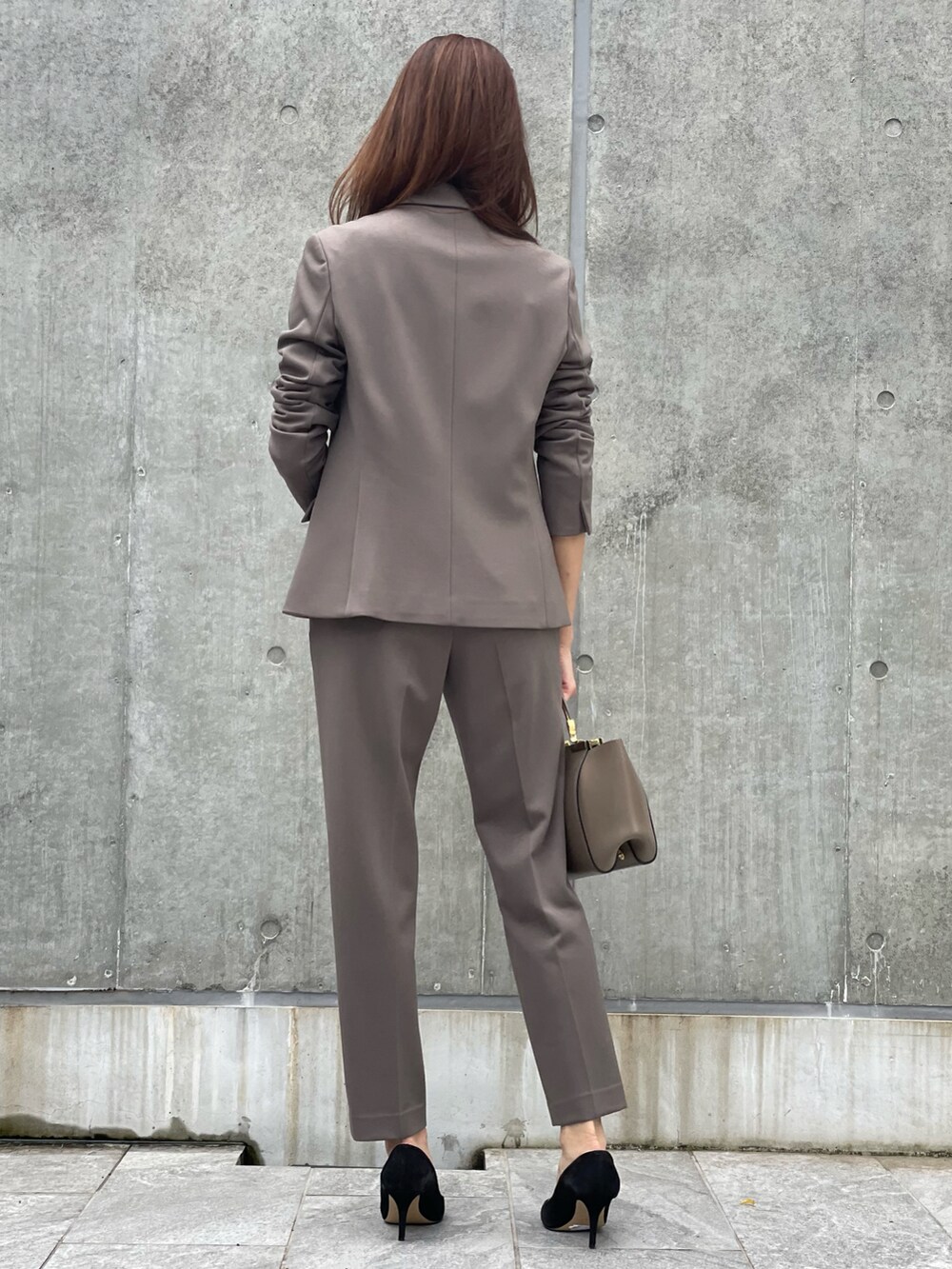 ブラウン系のテーラードジャケット、ブラック系のニット/セーター、ブラウン系のパンツを着用したレディースの秋コーディネートの3枚目の写真