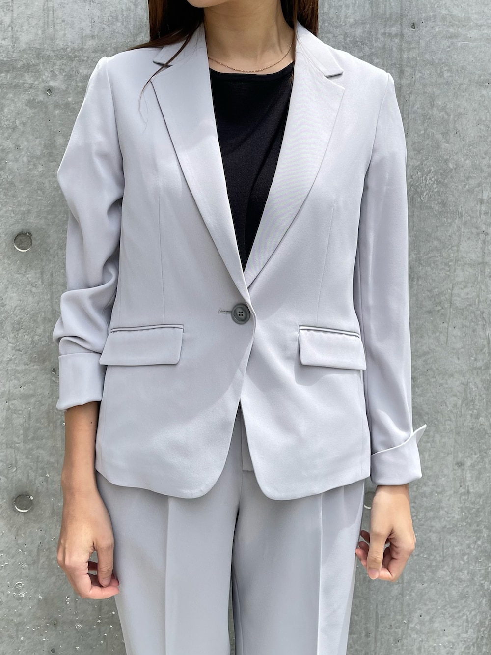 グレー系のテーラードジャケット、ブラック系のニット/セーター、グレー系のパンツを着用したレディースの春コーディネートの3枚目の写真