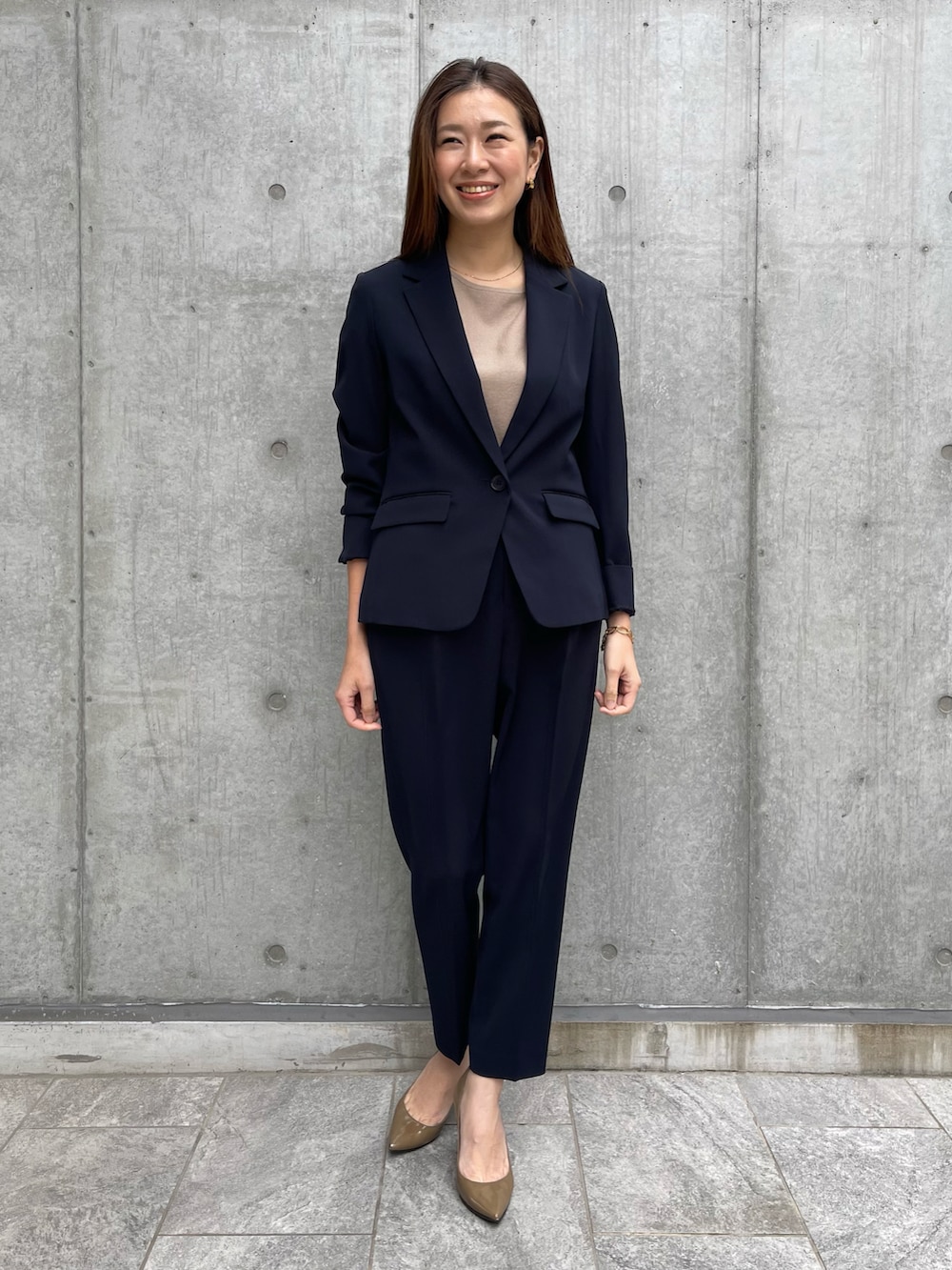 ブルー系のテーラードジャケット、ベージュ系のニット/セーター、ブルー系のパンツを着用したレディースの春コーディネートの2枚目の写真