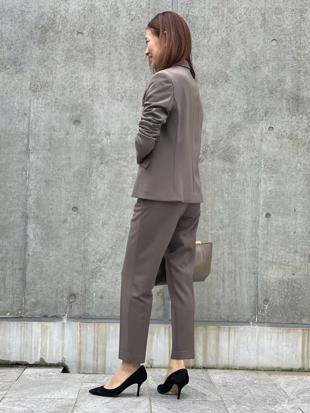 ブラウン系のテーラードジャケット、ブラック系のニット/セーター、ブラウン系のパンツを着用したレディースの秋コーディネートの2枚目の写真