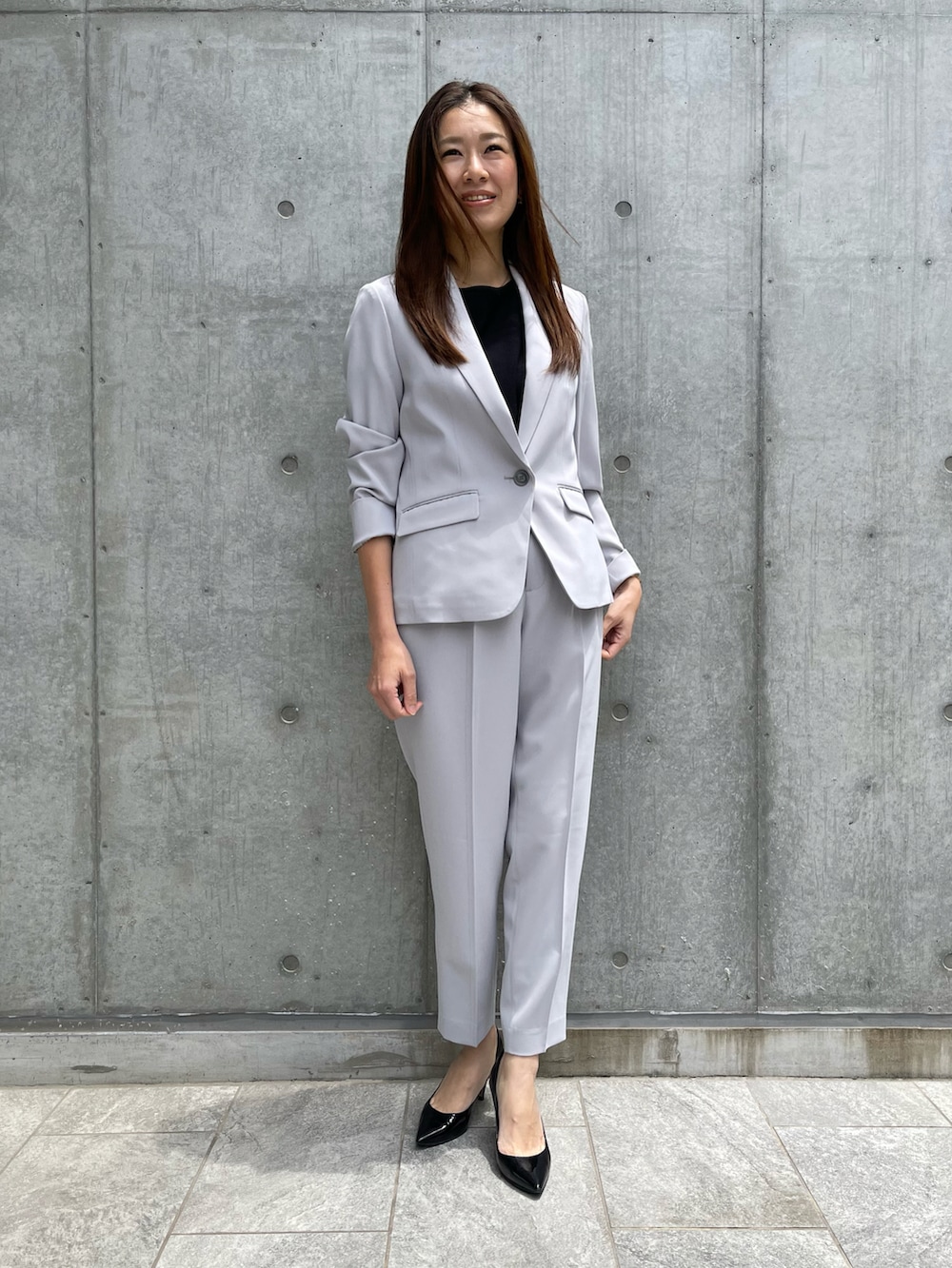 グレー系のテーラードジャケット、ブラック系のニット/セーター、グレー系のパンツを着用したレディースの春コーディネートの2枚目の写真
