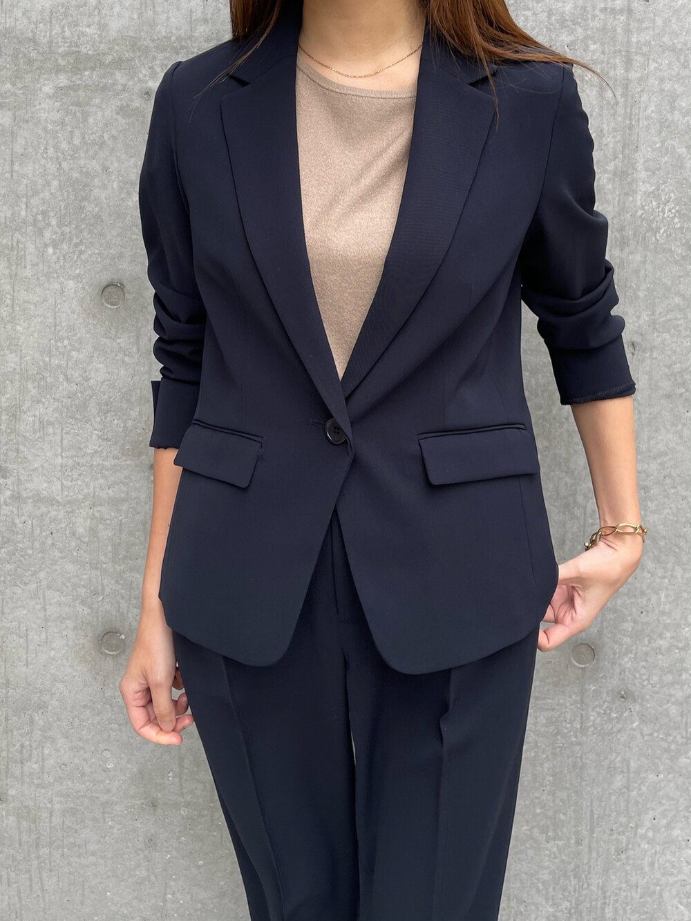 ブルー系のテーラードジャケット、ベージュ系のニット/セーター、ブルー系のパンツを着用したレディースの春コーディネートの3枚目の写真