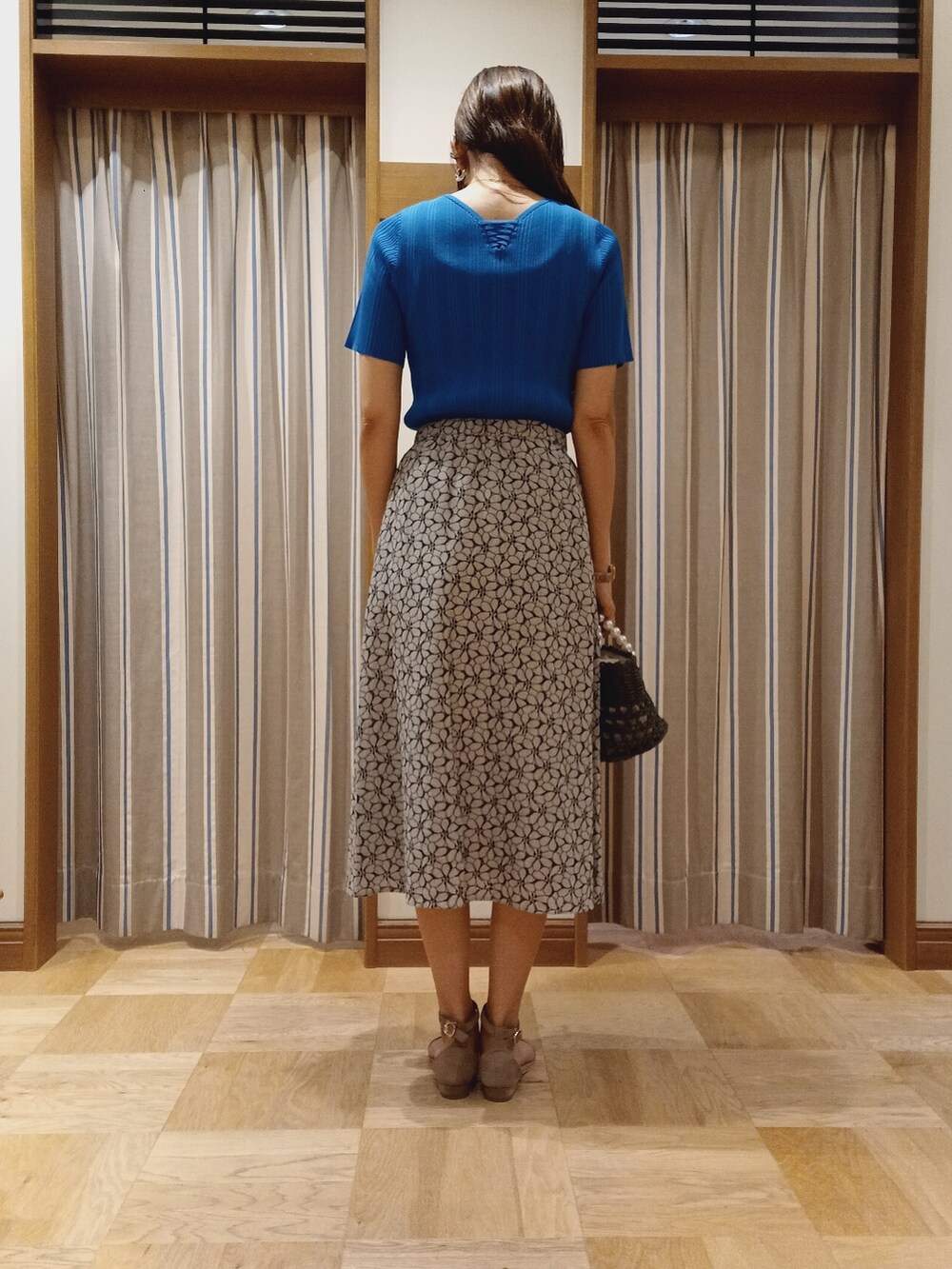 ブルー系のニット/セーター、ブラック系のスカートを着用したレディースの夏コーディネートの4枚目の写真