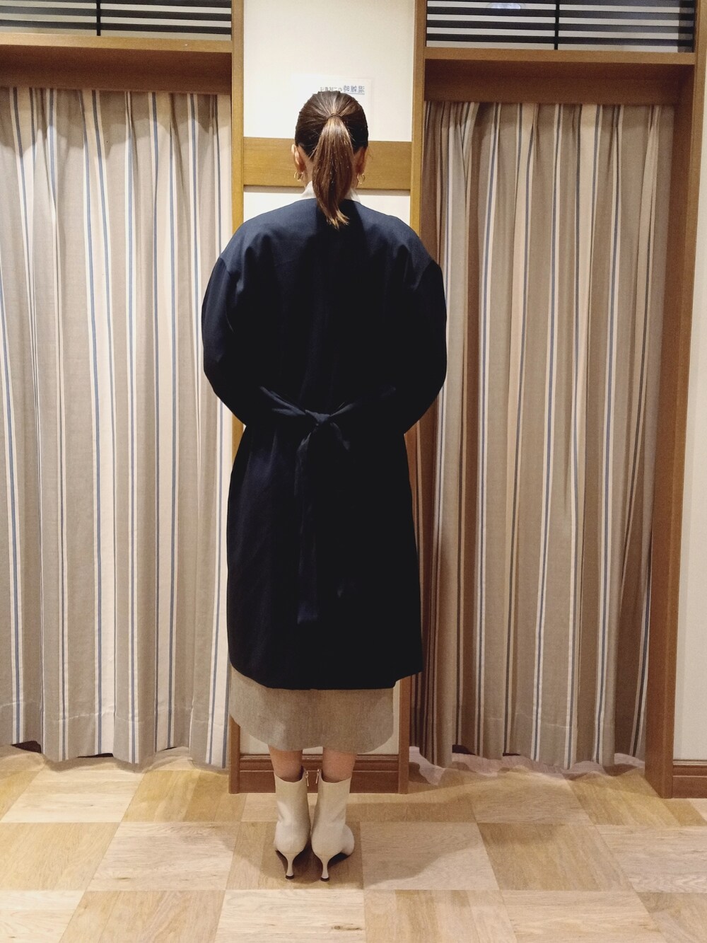 ブルー系のノーカラーコート、ベージュ系のワンピースを着用したレディースの秋コーディネートの4枚目の写真