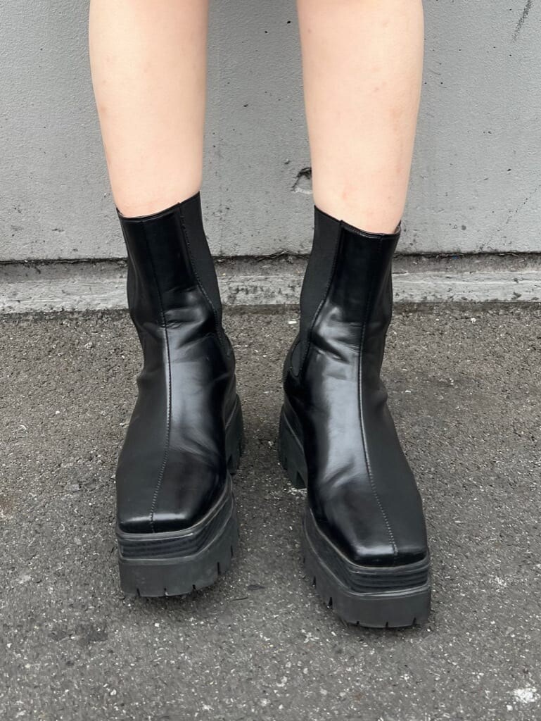 ブラック系のブーツ、ブラック系のジャンパースカート、ブラック系のTシャツ/カットソーを着用したレディースの夏コーディネートの5枚目の写真