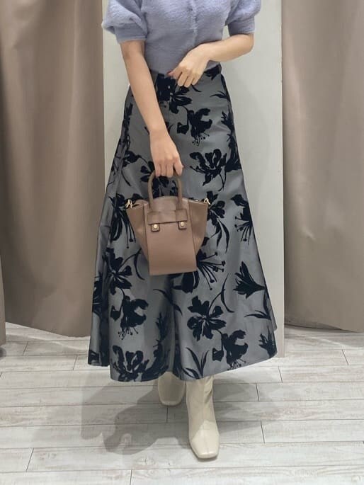 グレー系のスカート、ホワイト系のブーツ、ブラウン系のハンドバッグを着用したレディースの夏コーディネートの8枚目の写真