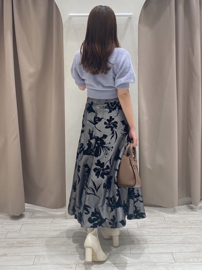 グレー系のスカート、ホワイト系のブーツ、ブラウン系のハンドバッグを着用したレディースの夏コーディネートの4枚目の写真