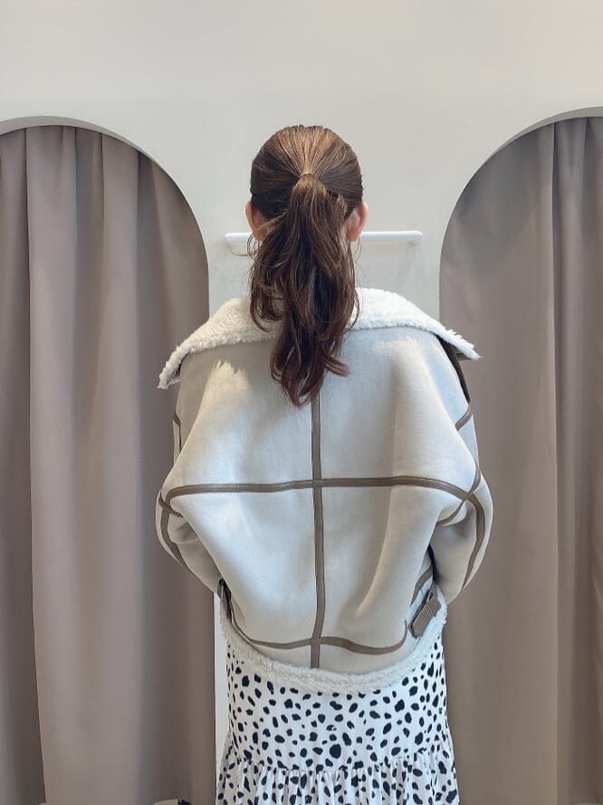 ブラウン系のブーツ、ベージュ系のムートンコート、ホワイト系のワンピースを着用したレディースの夏コーディネートの6枚目の写真