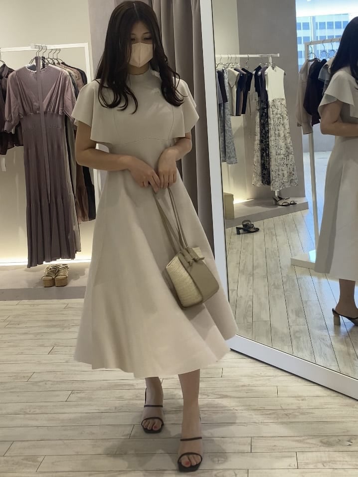 ホワイト系のワンピース、ベージュ系のトートバッグ、ブラウン系のサンダルを着用したレディースの夏コーディネートの2枚目の写真