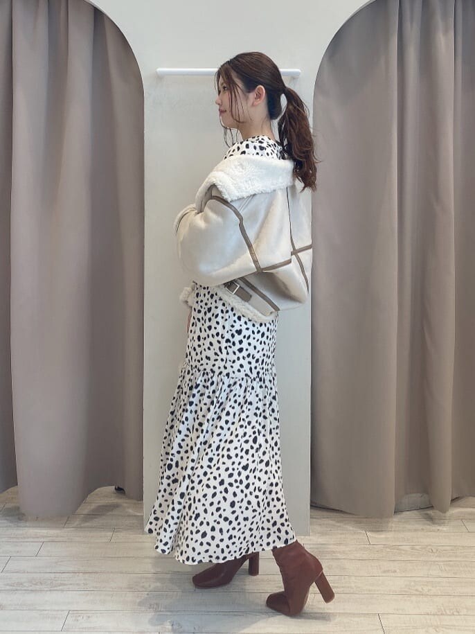 ブラウン系のブーツ、ベージュ系のムートンコート、ホワイト系のワンピースを着用したレディースの夏コーディネートの2枚目の写真