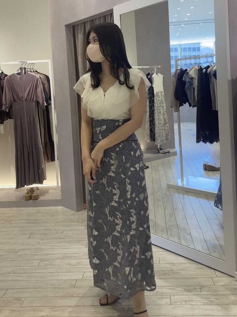 ベージュ系のトートバッグ、ホワイト系のカーディガン/ボレロ、ブルー系のスカートを着用したレディースの夏コーディネートの3枚目の写真