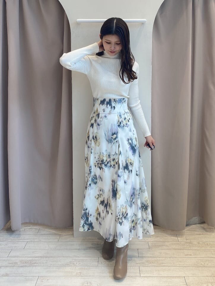 ホワイト系のスカート、ホワイト系のニット/セーター、ブラウン系のダウンジャケット/コートを着用したレディースの秋コーディネートの3枚目の写真