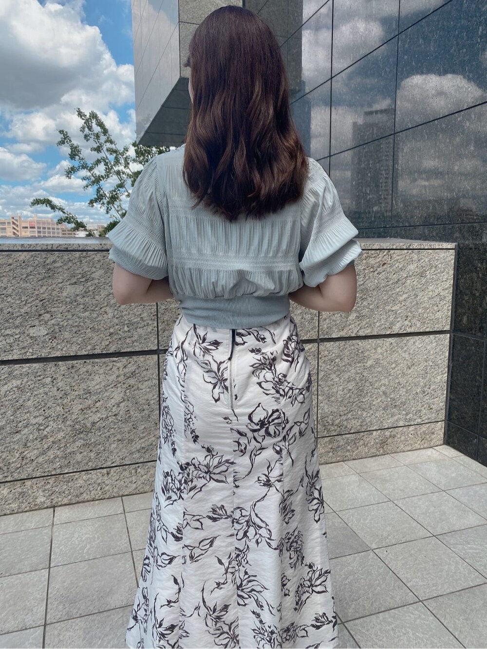 ホワイト系のスカート、ホワイト系のその他シューズ、グリーン系のニット/セーターを着用したレディースの夏コーディネートの2枚目の写真