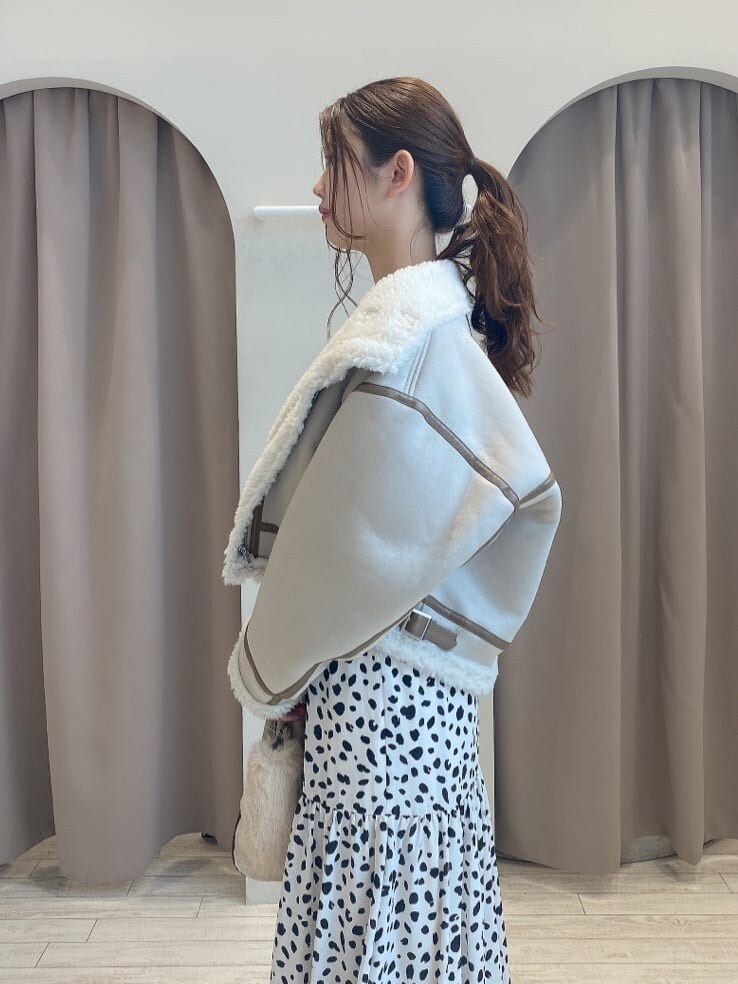 ブラウン系のブーツ、ベージュ系のムートンコート、ホワイト系のワンピースを着用したレディースの夏コーディネートの5枚目の写真