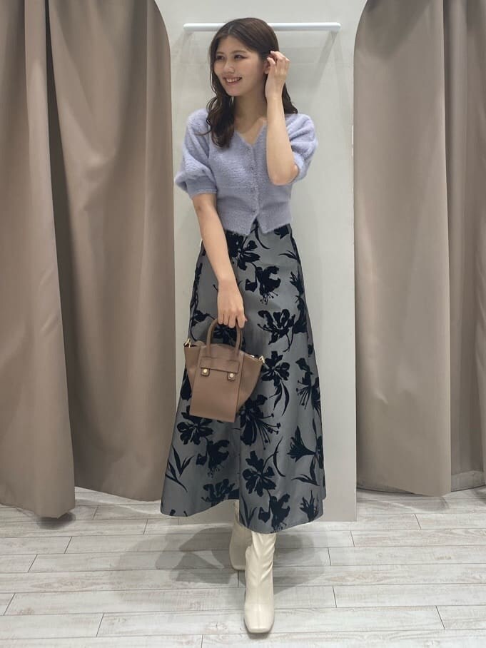 グレー系のスカート、ホワイト系のブーツ、ブラウン系のハンドバッグを着用したレディースの夏コーディネートの3枚目の写真