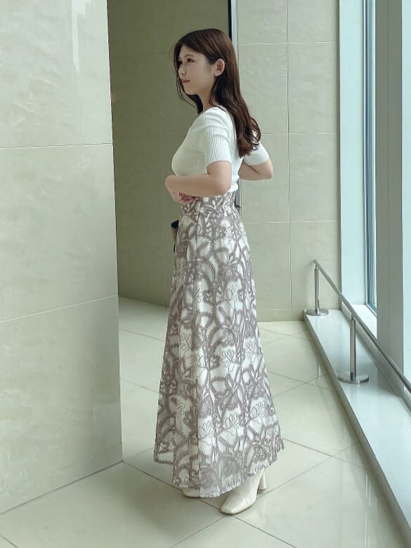 ホワイト系のスカート、ホワイト系のブーツ、ブラウン系のハンドバッグを着用したレディースの夏コーディネートの2枚目の写真