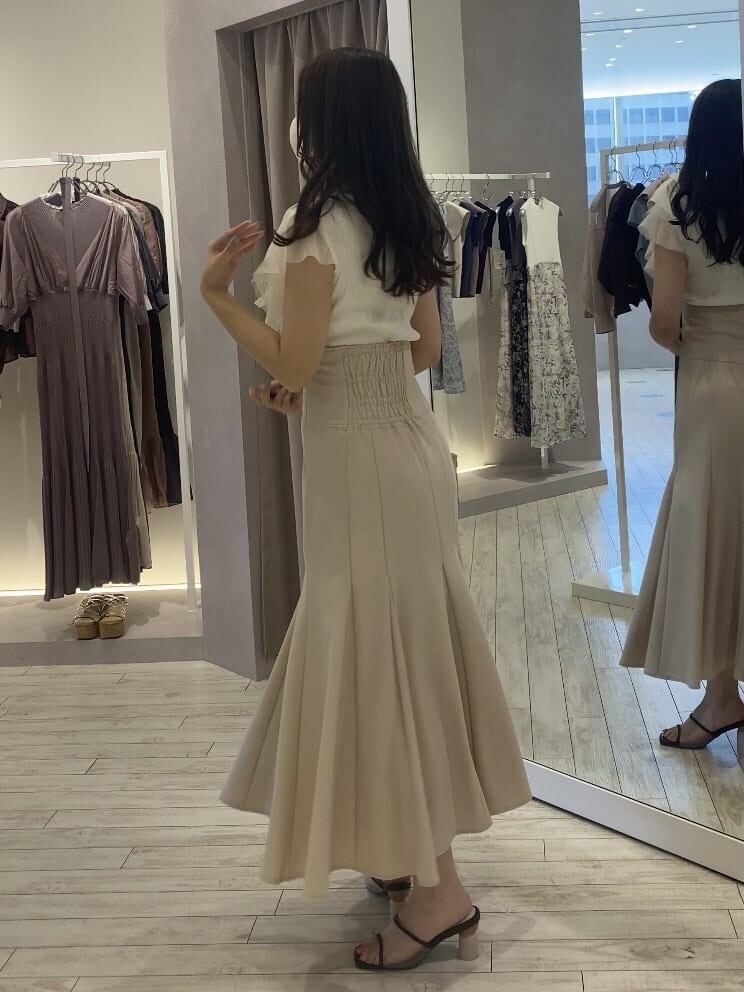 ピンク系のスカート、ブラウン系のサンダル、ホワイト系のカーディガン/ボレロを着用したレディースの夏コーディネートの2枚目の写真