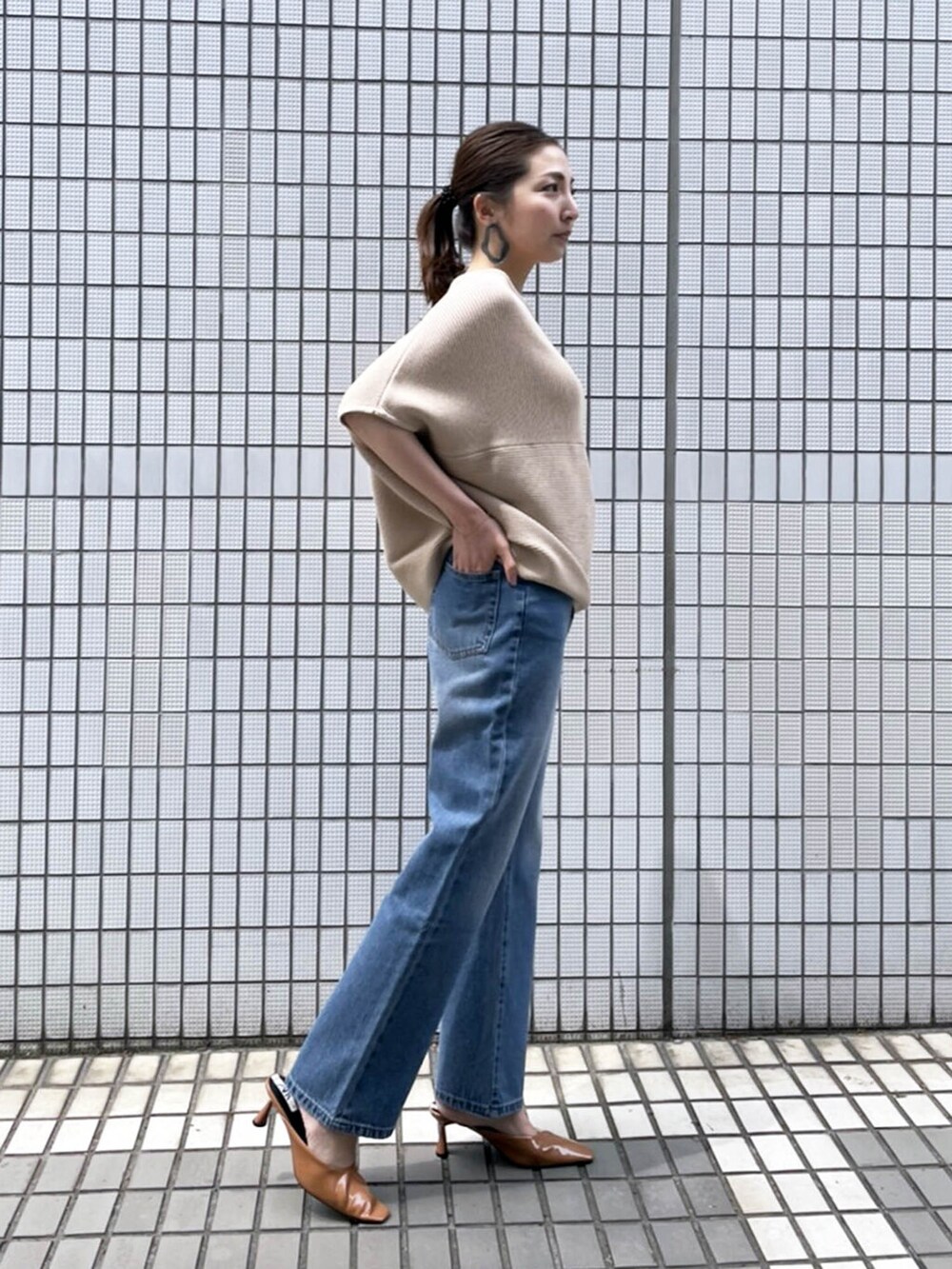 ブルー系のデニムパンツ、ベージュ系のニット/セーターを着用したレディースの春コーディネートの2枚目の写真