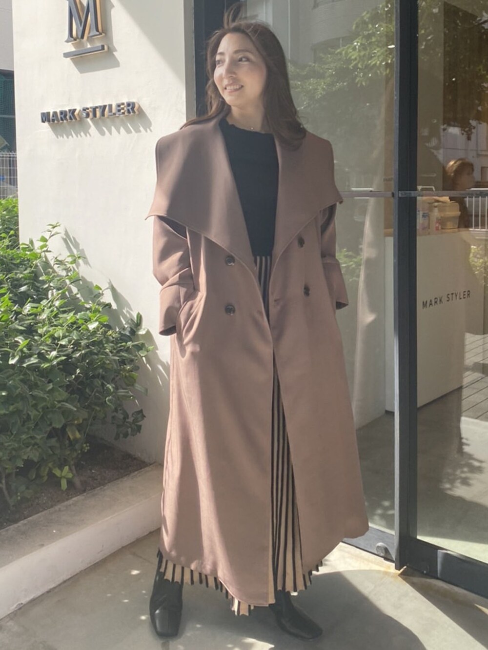 ブラック系のスカート、ベージュ系のその他アウター、ブラック系のニット/セーターを着用したレディースの秋コーディネートの2枚目の写真