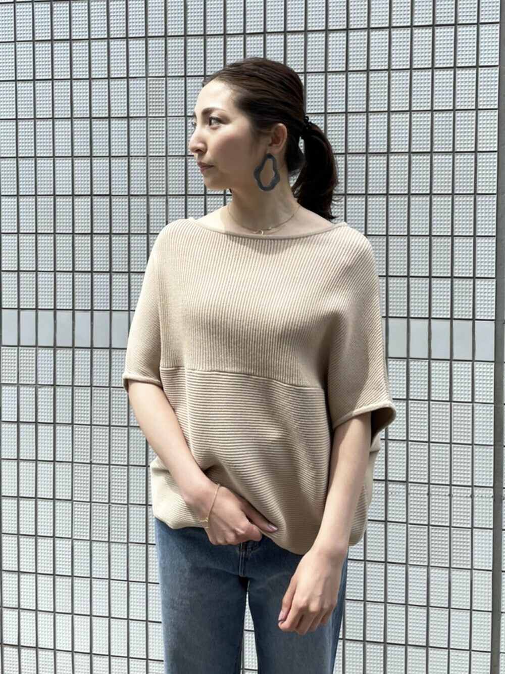 ブルー系のデニムパンツ、ベージュ系のニット/セーターを着用したレディースの春コーディネートの3枚目の写真