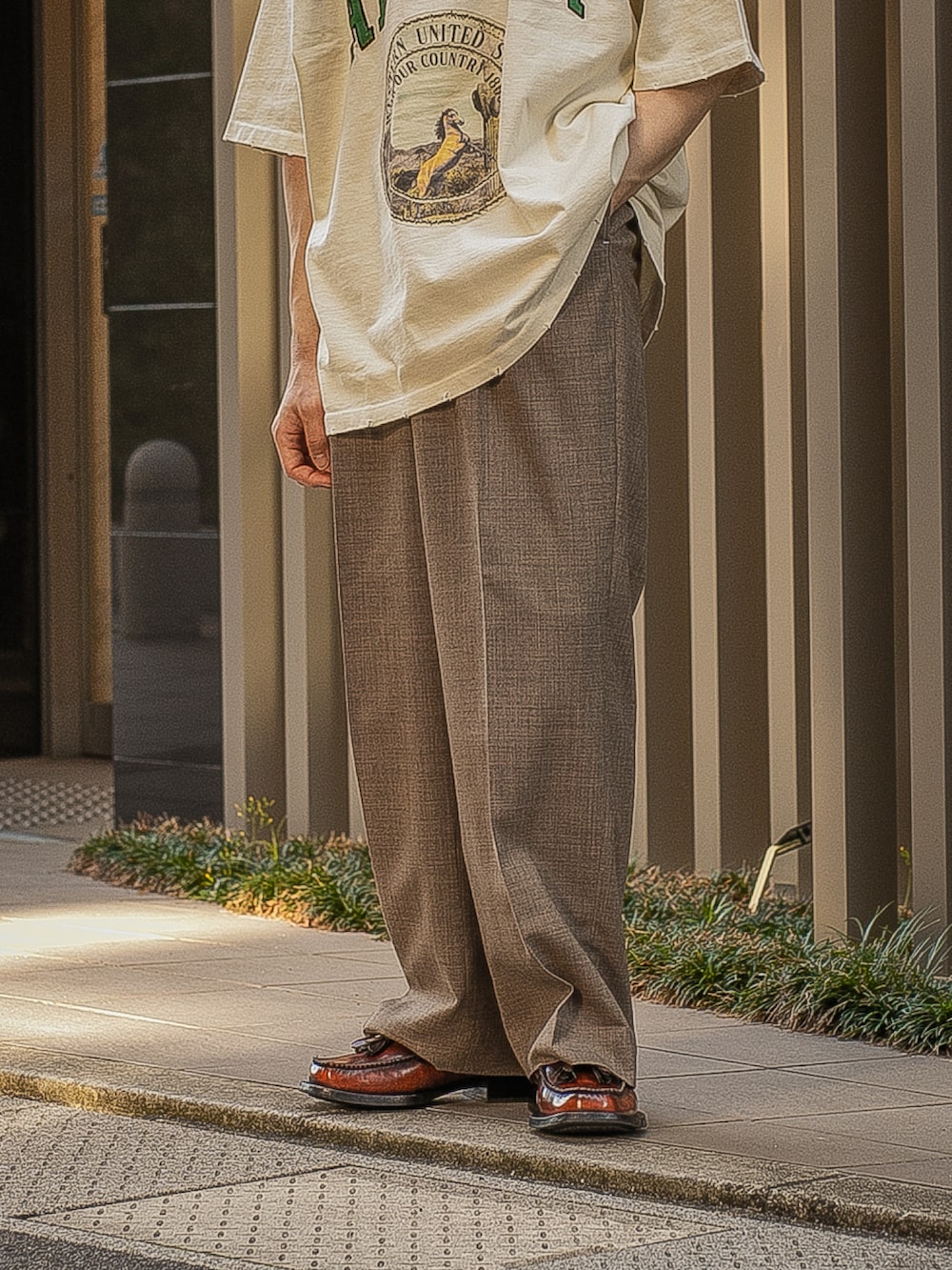 ベージュ系のTシャツ/カットソー、ブラウン系のスラックス、ブラウン系のローファーを着用したメンズの春コーディネートの4枚目の写真