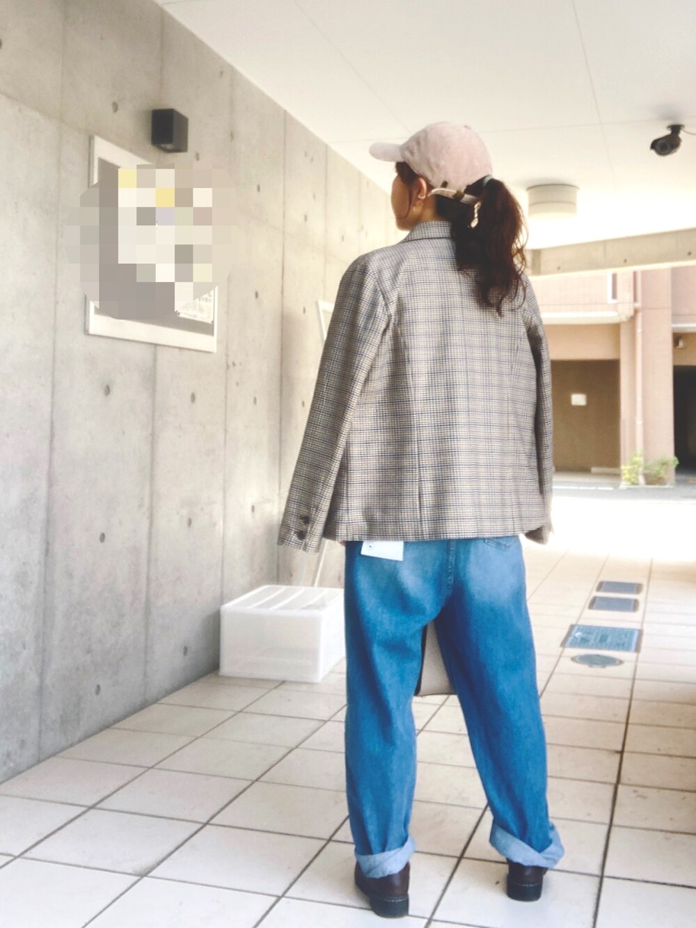 ブルー系のデニムパンツ、ベージュ系のハンドバッグ、グリーン系のニット/セーターを着用したレディースの春コーディネートの2枚目の写真