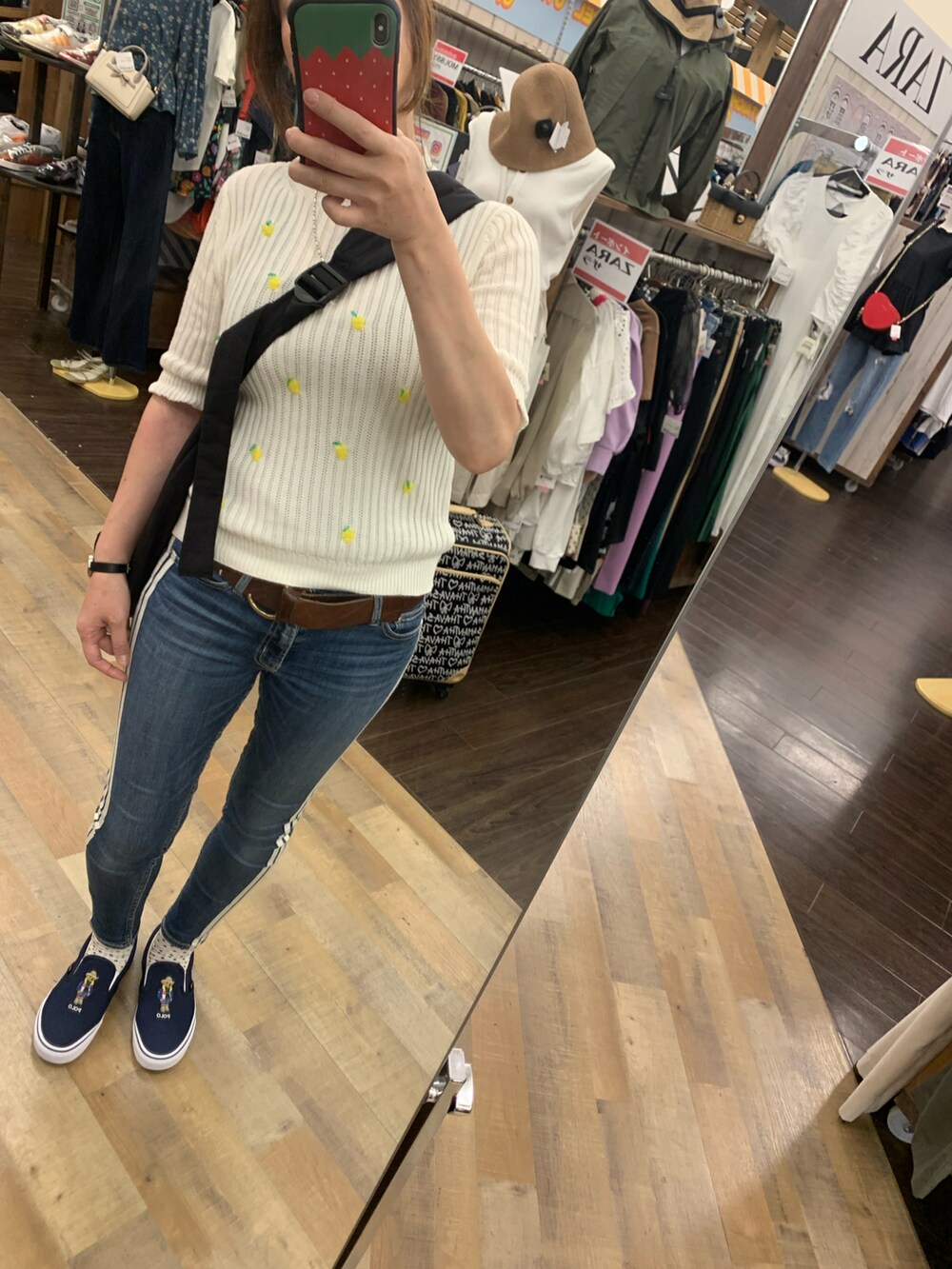 ブルー系のデニムパンツ、ブラック系のショルダーバッグ、ホワイト系のニット/セーターを着用したレディースの秋コーディネートの2枚目の写真