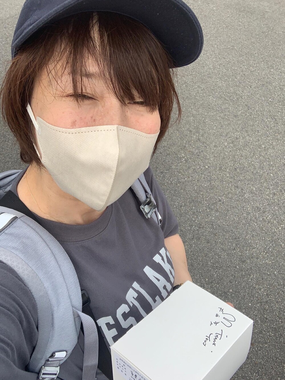 グレー系のTシャツ/カットソー、グレー系のバックパック/リュック、ブルー系のキャップを着用したレディースの夏コーディネートの2枚目の写真