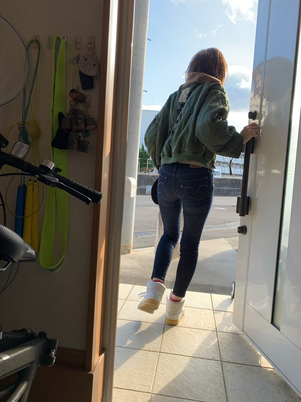 ブルー系のデニムパンツ、ホワイト系のスニーカー、グリーン系のブルゾンを着用したレディースの冬コーディネートの2枚目の写真