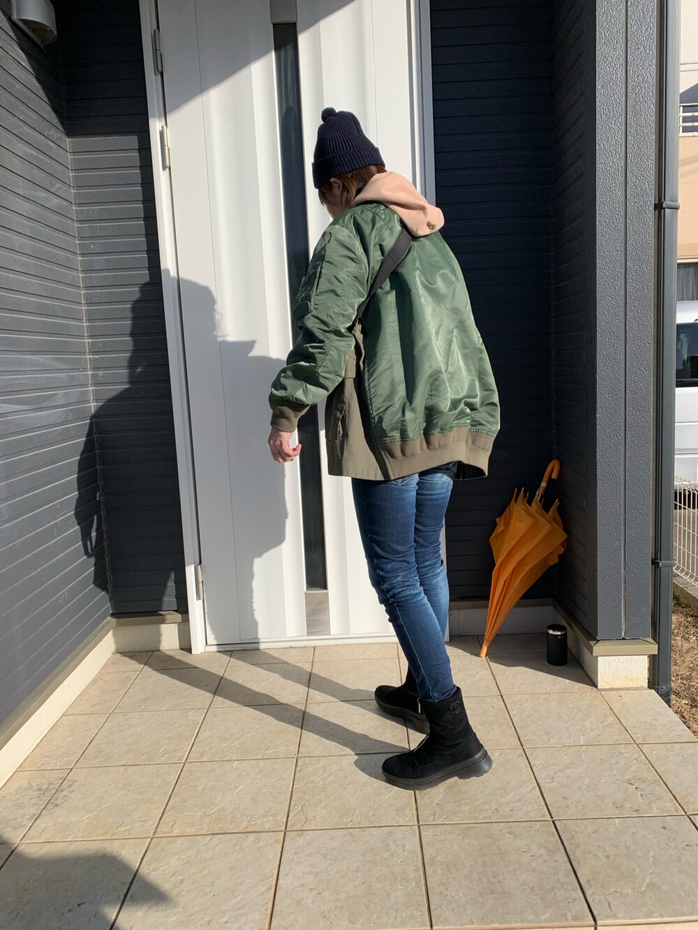 グリーン系のMA-1、ブルー系のデニムパンツ、ブラック系のブーツを着用したレディースの冬コーディネートの2枚目の写真