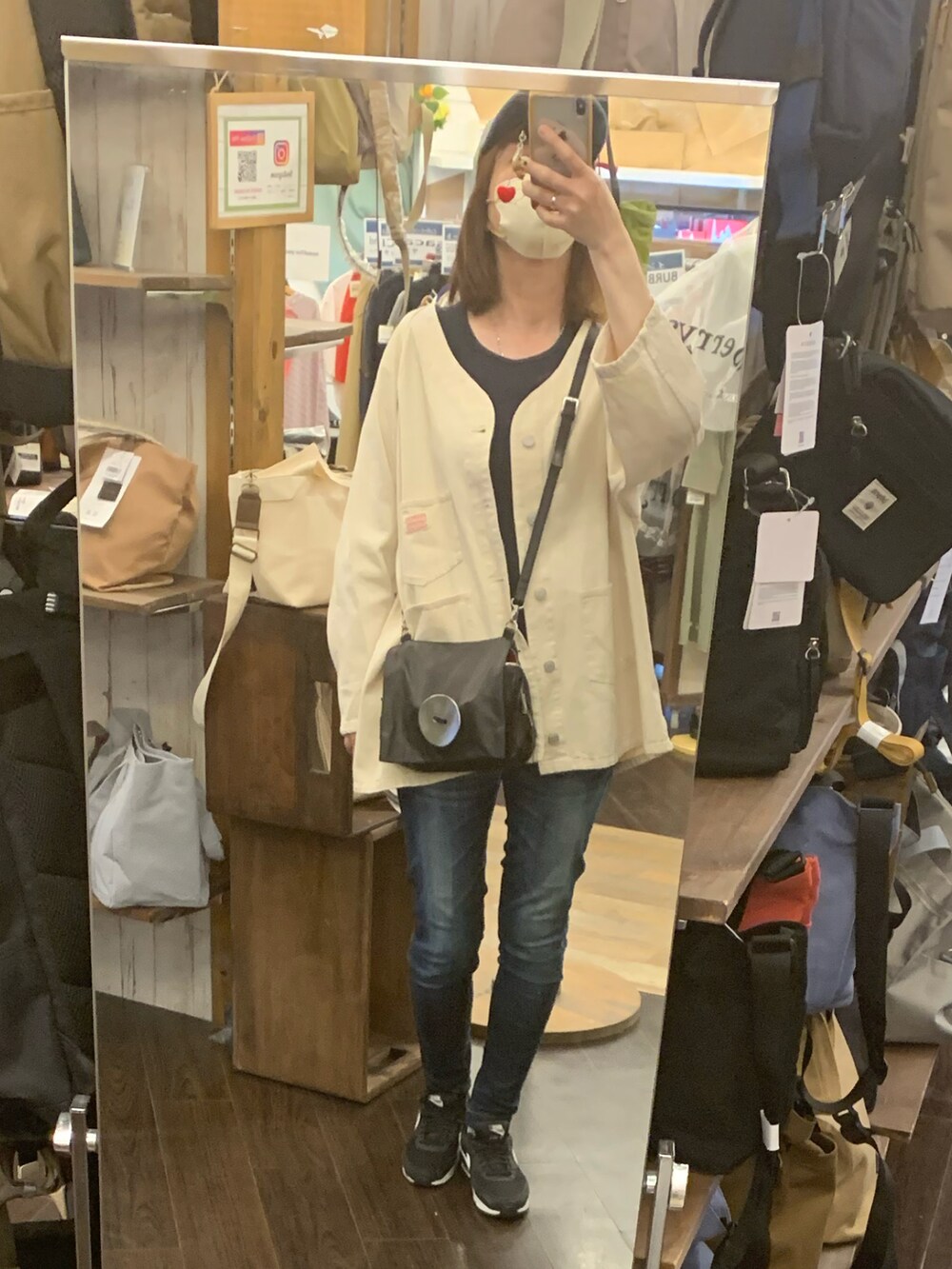 ブルー系のデニムパンツ、ブラック系のスニーカー、ブラック系のショルダーバッグを着用したレディースの春コーディネートの2枚目の写真