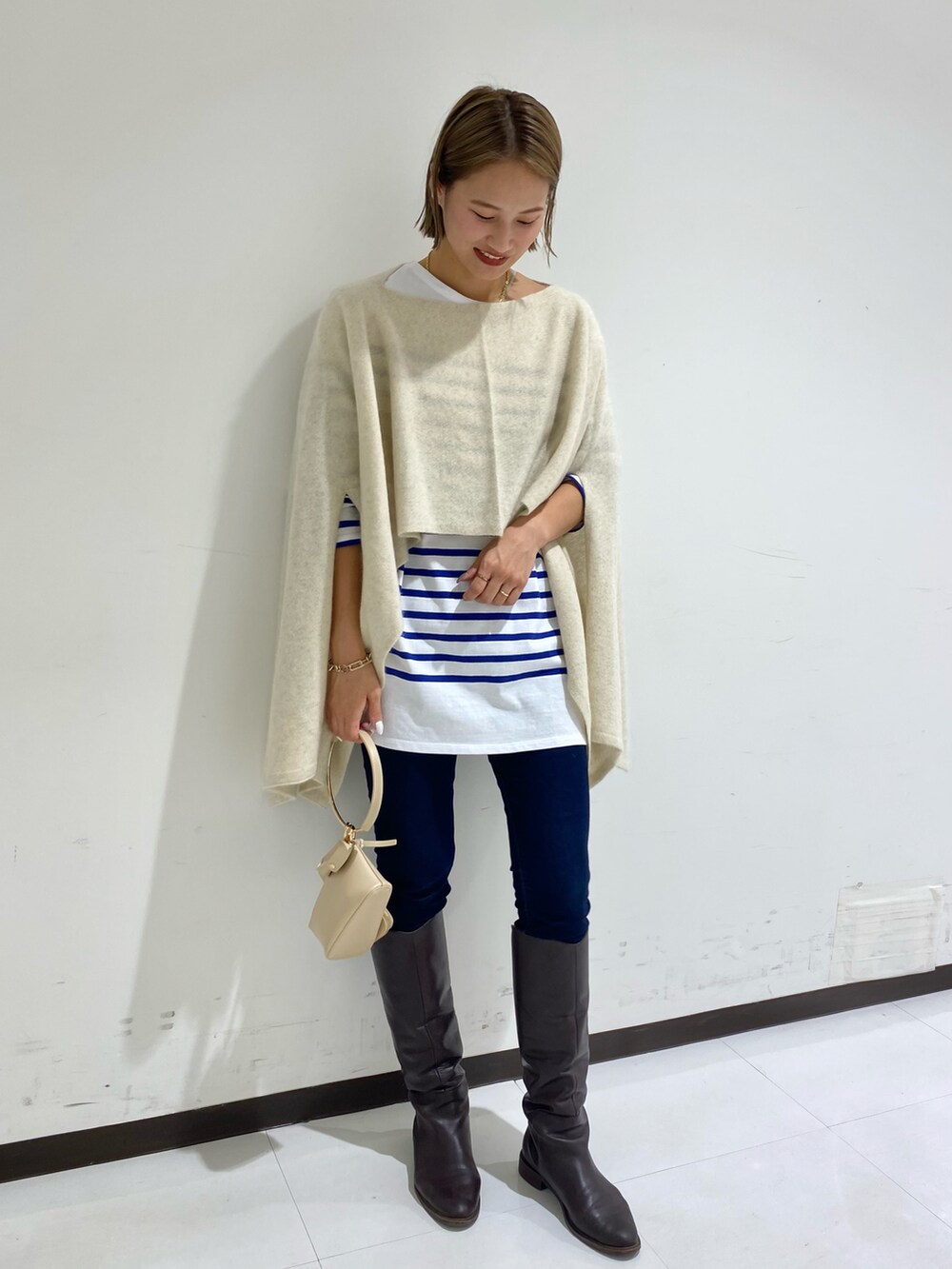 ブルー系のTシャツ/カットソー、ベージュ系のハンドバッグ、ホワイト系のストール/ショールを着用したレディースの秋コーディネートの2枚目の写真