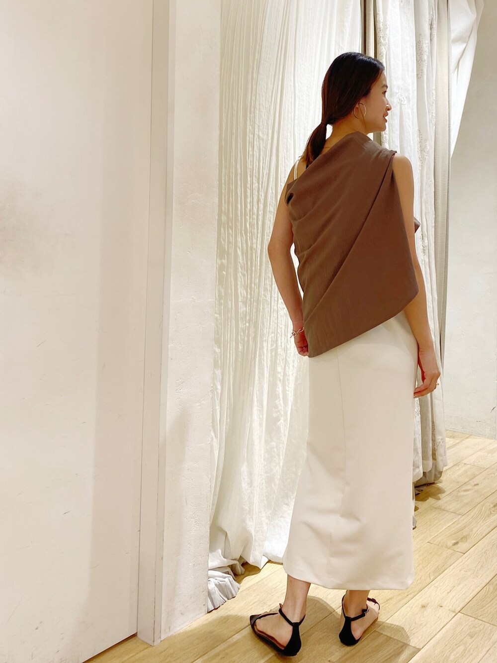 ホワイト系のシャツ/ブラウス、ブラック系のスカート、ブラック系のサンダルを着用したレディースの夏コーディネートの2枚目の写真