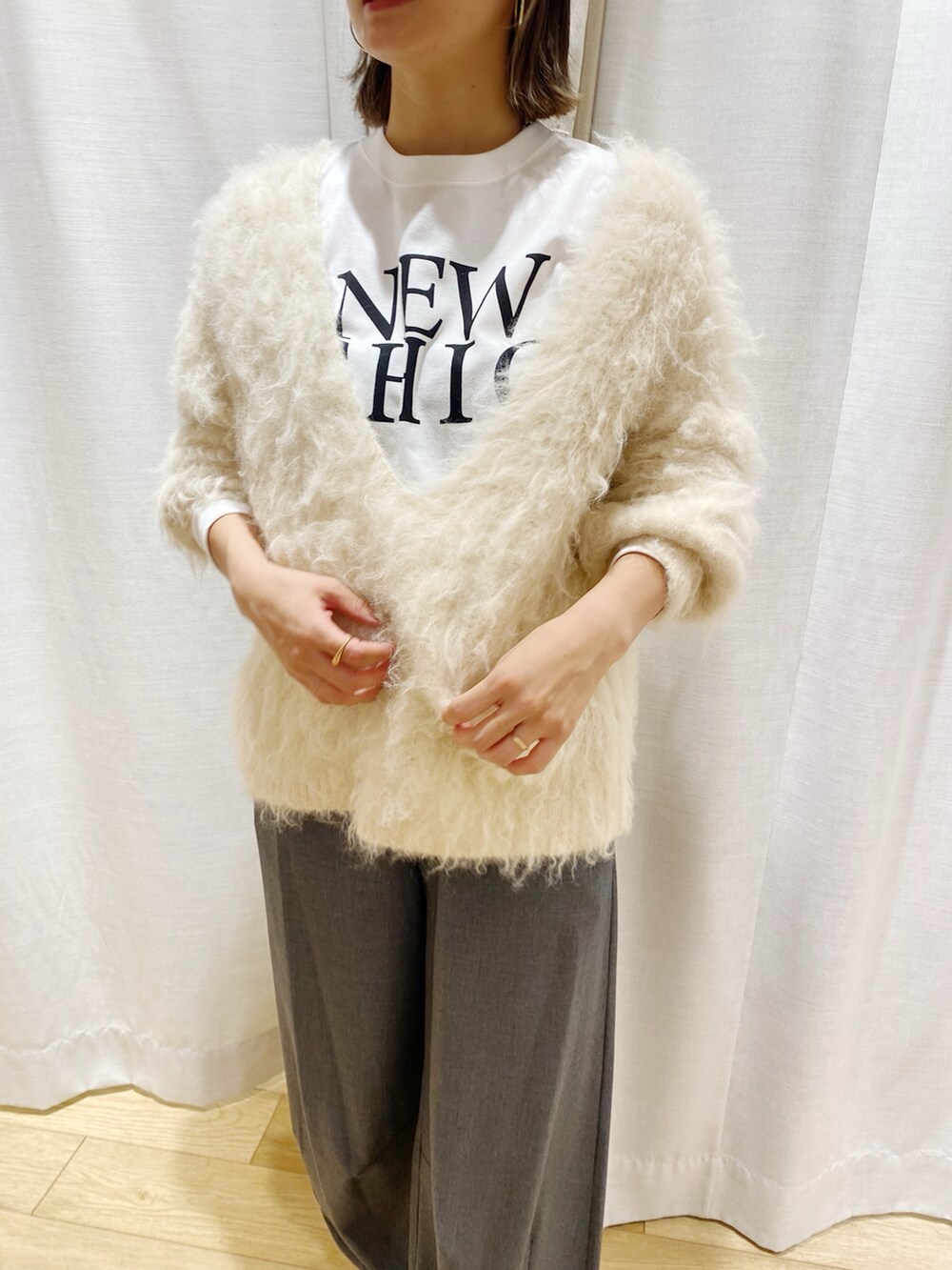 ホワイト系のニット/セーター、グレー系のスラックスを着用したレディースの冬コーディネートの2枚目の写真