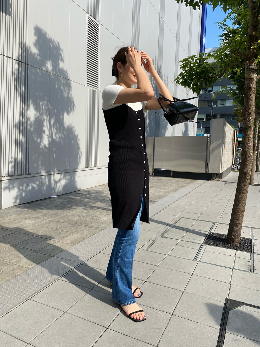 ブラック系のニット/セーター、ブルー系のデニムパンツを着用したレディースの春コーディネートの2枚目の写真