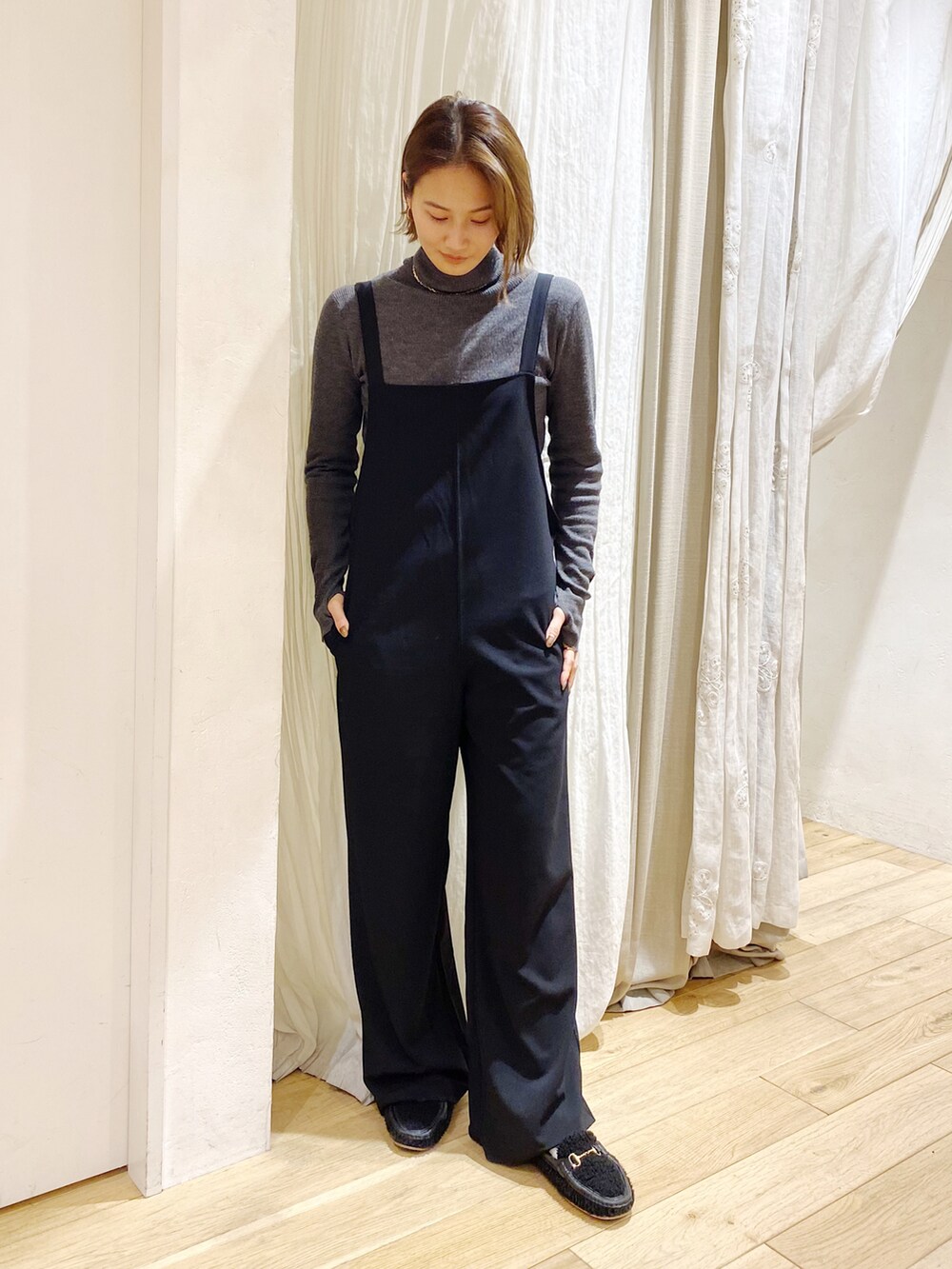 ブラック系のサロペット/オーバーオール、グレー系のニット/セーターを着用したレディースの冬コーディネートの2枚目の写真