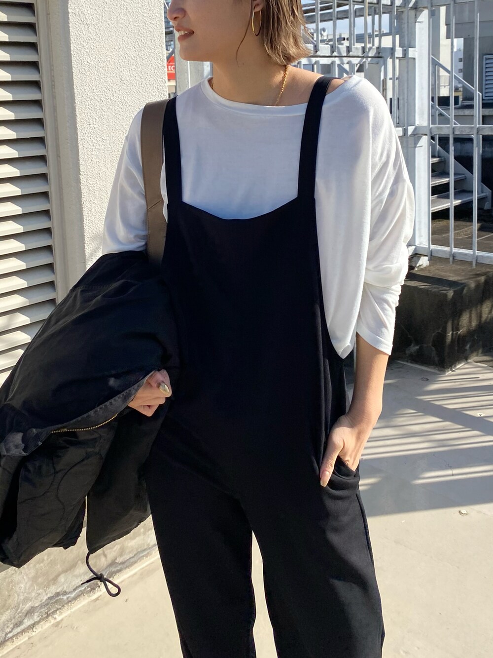 ホワイト系のTシャツ/カットソー、ブラック系のサロペット/オーバーオールを着用したレディースの冬コーディネートの2枚目の写真