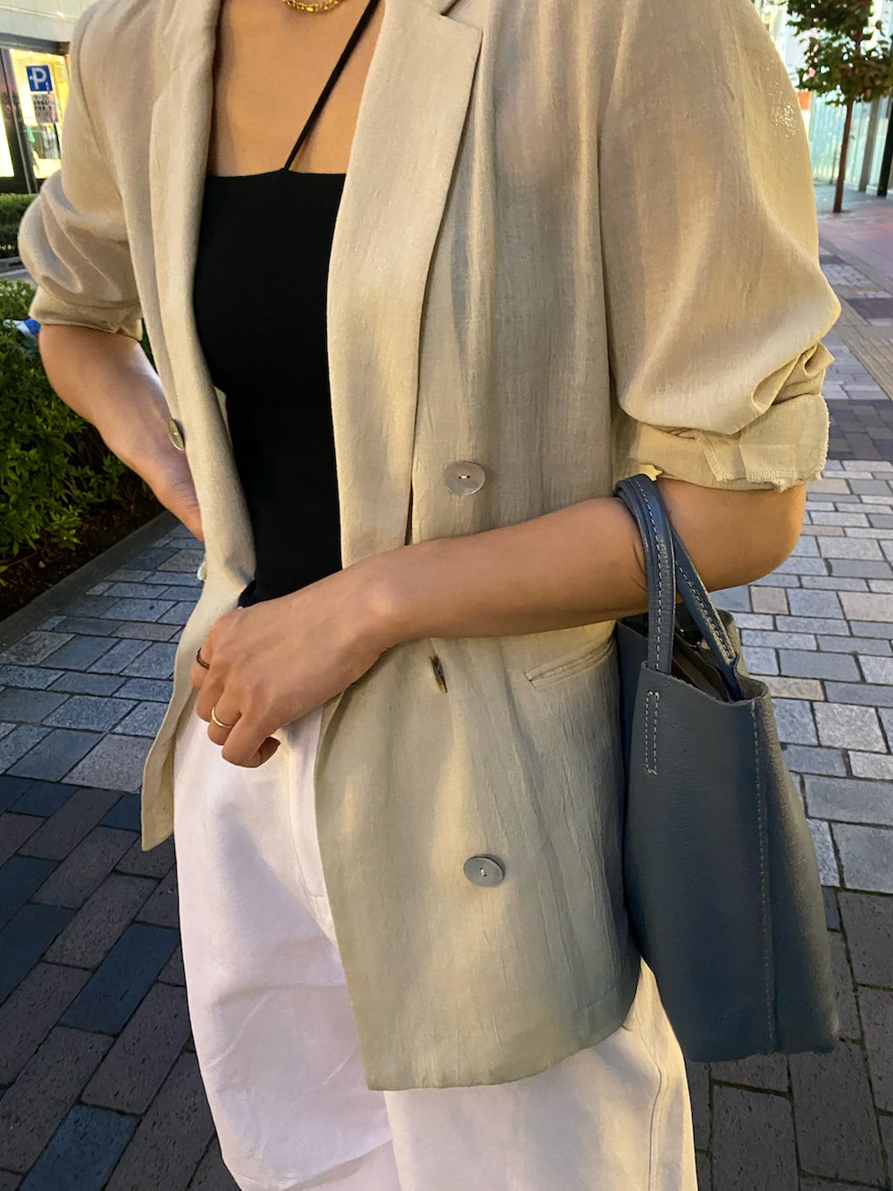 グレー系のテーラードジャケット、ホワイト系のパンツを着用したレディースの夏コーディネートの3枚目の写真