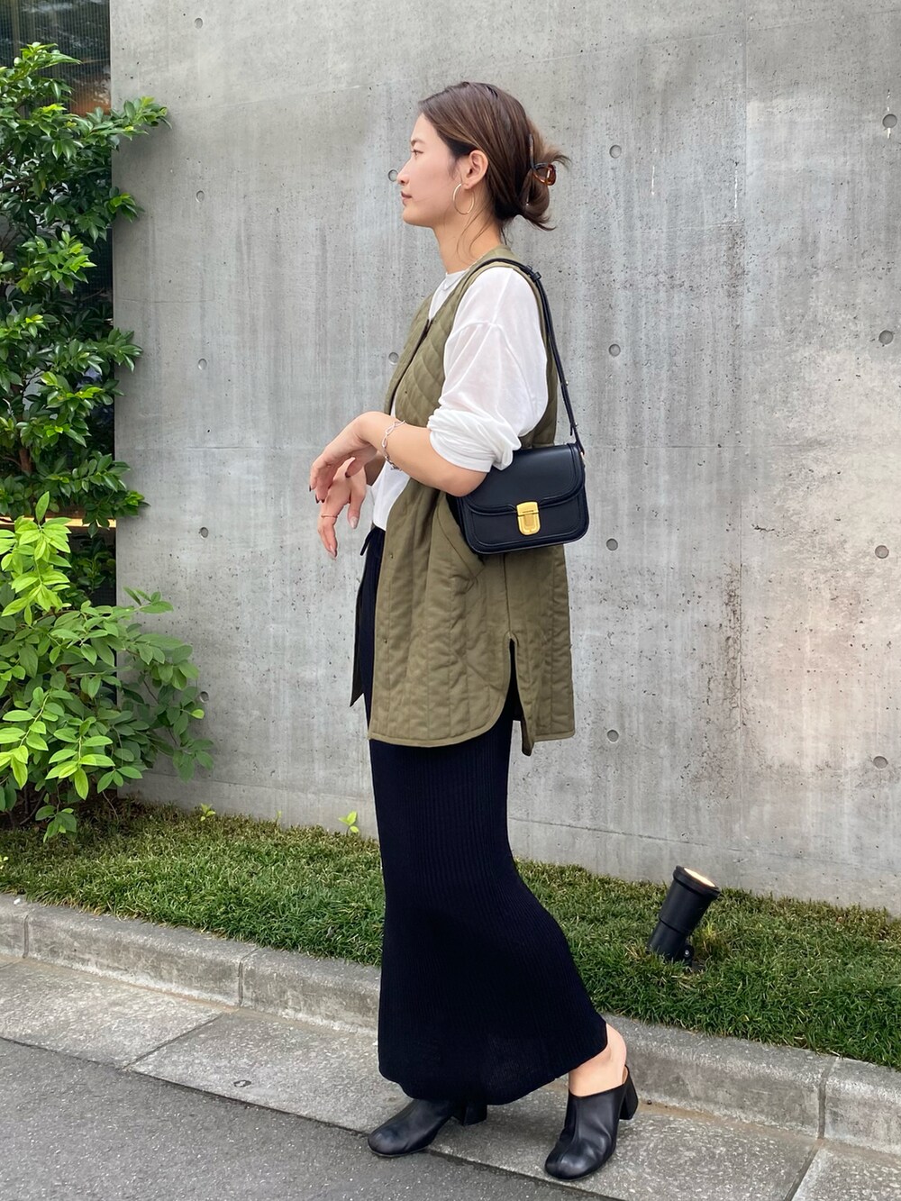 ホワイト系のTシャツ/カットソー、ブラック系のスカート、グリーン系のベストを着用したレディースの秋コーディネートの3枚目の写真