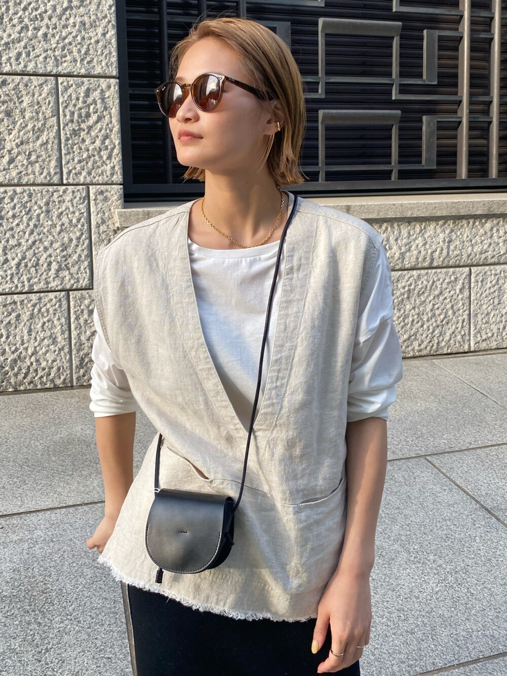 ベージュ系のベスト、ホワイト系のTシャツ/カットソー、ブラック系のスカートを着用したレディースの春コーディネートの2枚目の写真