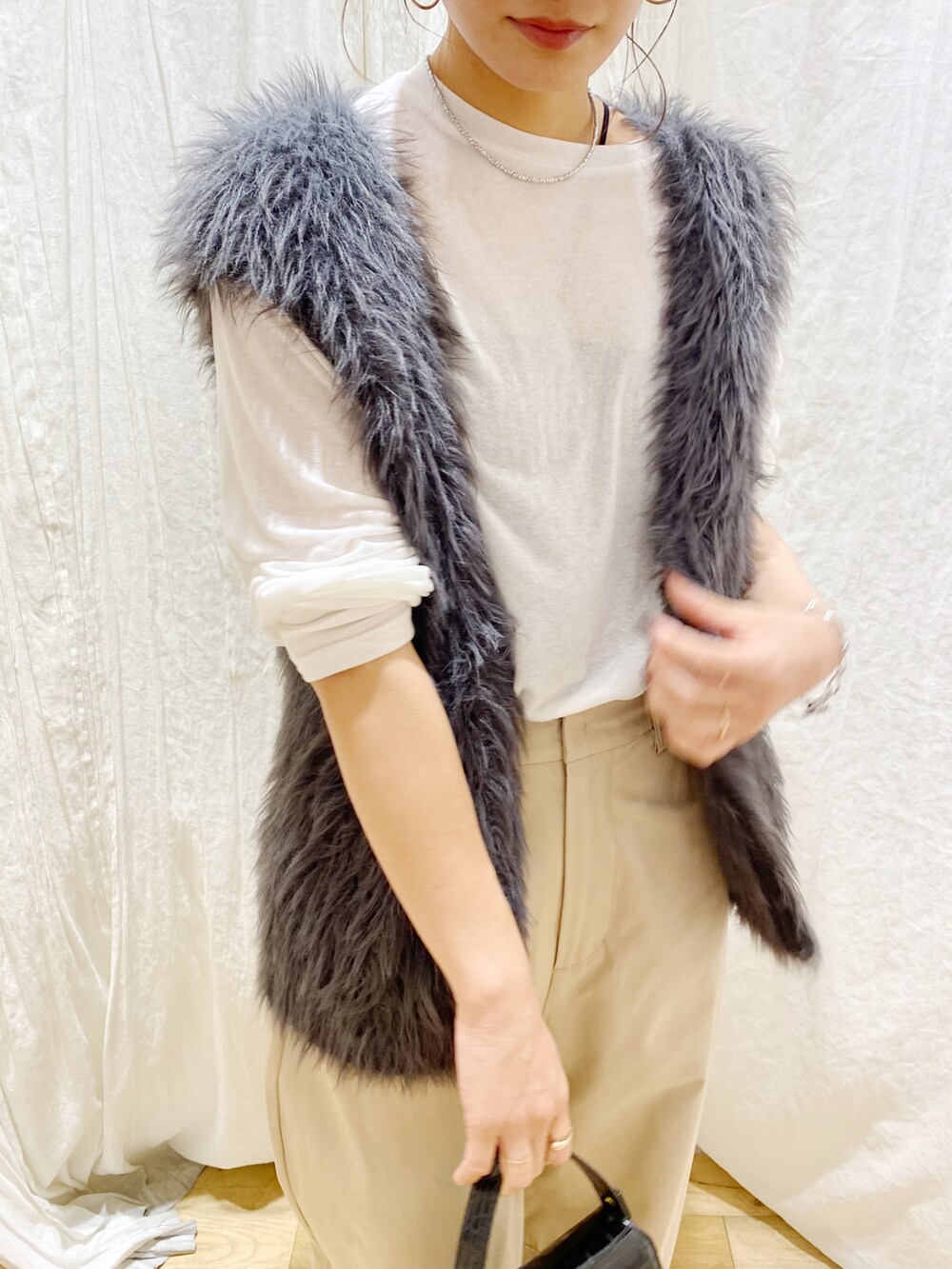 ホワイト系のTシャツ/カットソー、グレー系のベスト、ベージュ系のチノパンツを着用したレディースの秋コーディネートの2枚目の写真