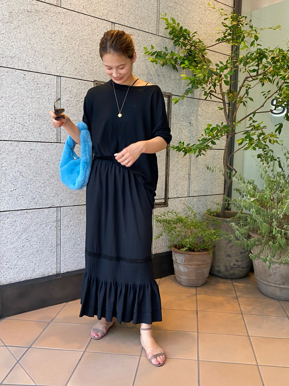 ブラック系のスカート、ホワイト系のハンドバッグを着用したレディースの夏コーディネートの2枚目の写真