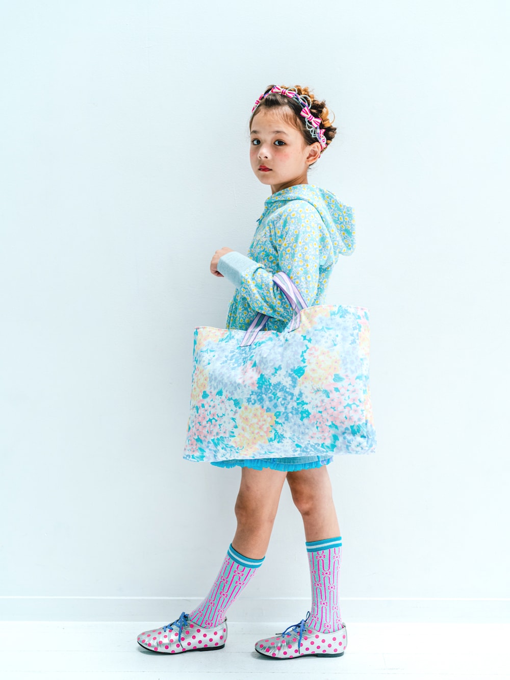 パープル系のトートバッグ、ブルー系のスカート、ブルー系のパーカーを着用したキッズの冬コーディネートの2枚目の写真