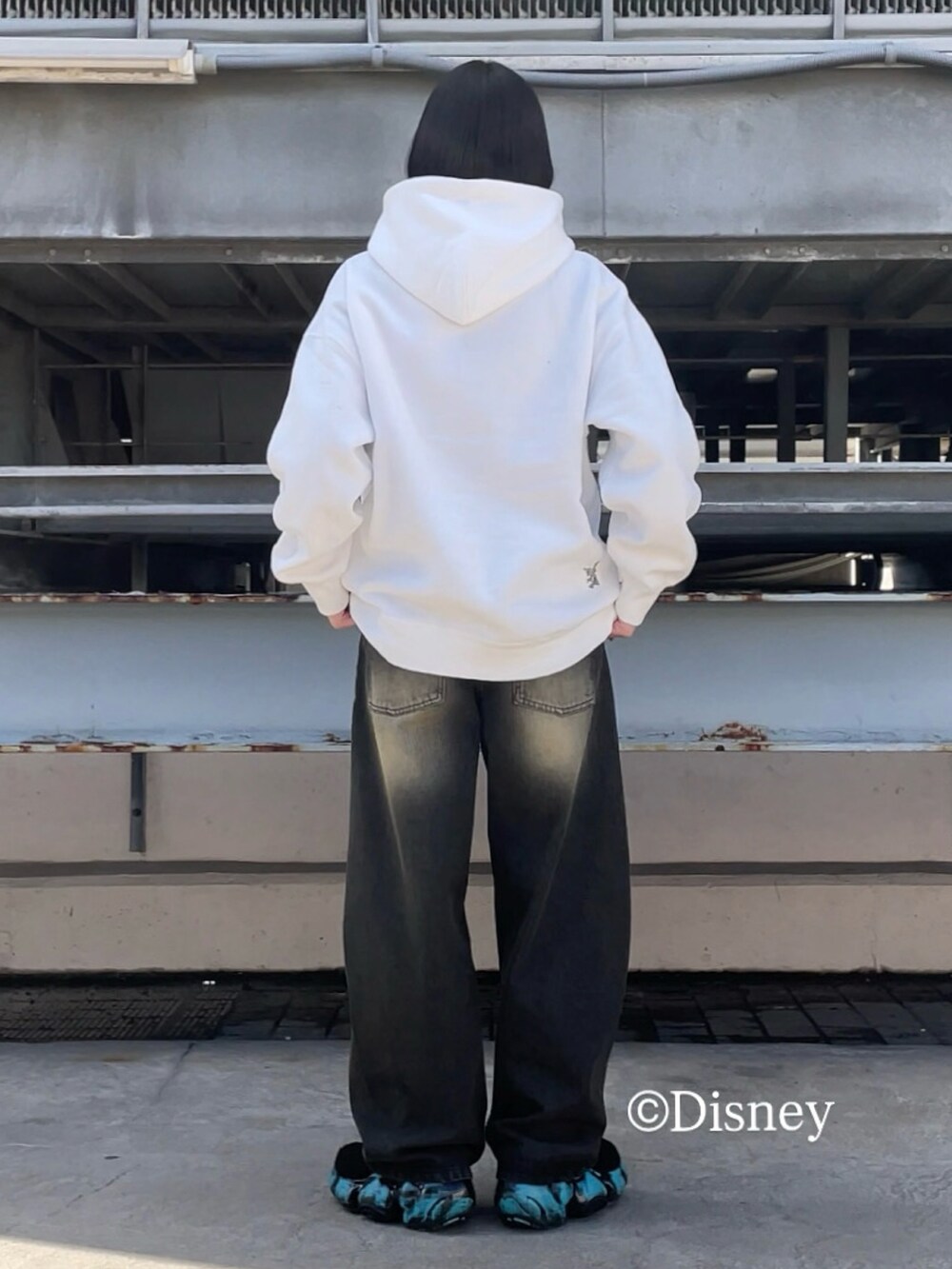 ホワイト系のパーカー、ブラック系のデニムパンツを着用したレディースの冬コーディネートの3枚目の写真