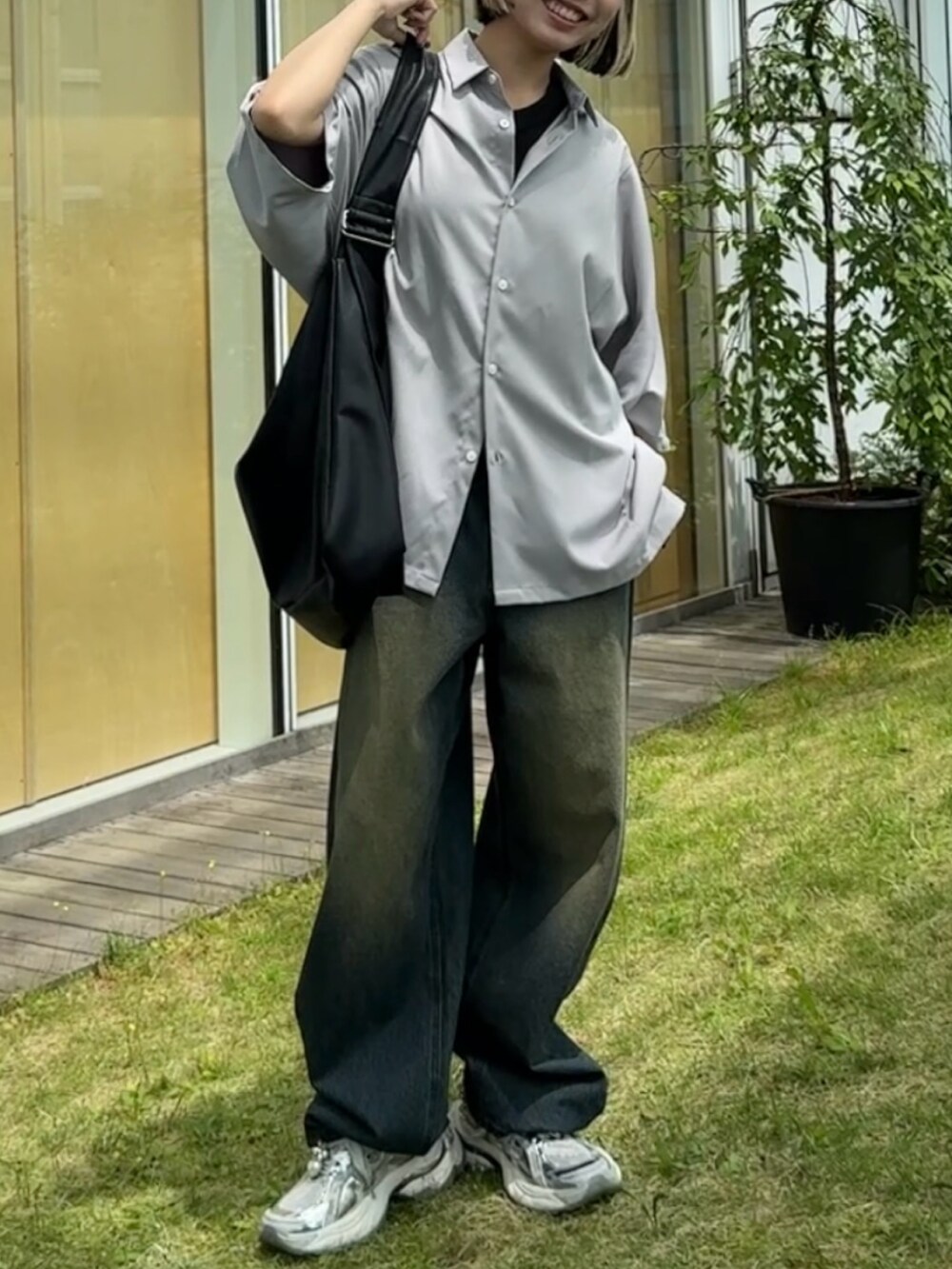 グレー系のシャツ/ブラウス、ブラック系のショルダーバッグ、ブルー系のデニムパンツを着用したレディースの春コーディネートの3枚目の写真