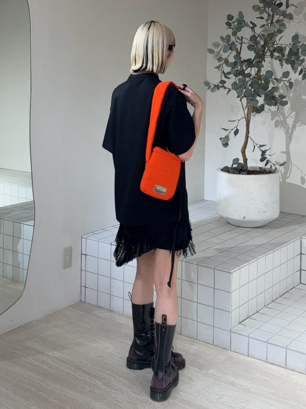 ブラック系のTシャツ/カットソー、オレンジ系のショルダーバッグ、ブラック系のブーツを着用したレディースの夏コーディネートの3枚目の写真